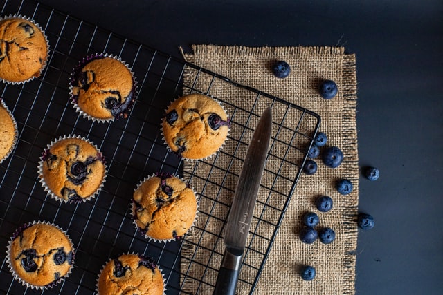 Blaubeermuffins auf einem Gitter umgeben von Blaubeeren