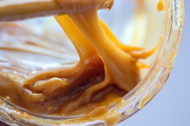 Mit einem Stäbchen wird in einem Glas klebrigem Karamell gerührt