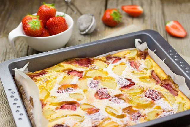 Ein Kuchen vom Blech, drumherum Erdbeeren