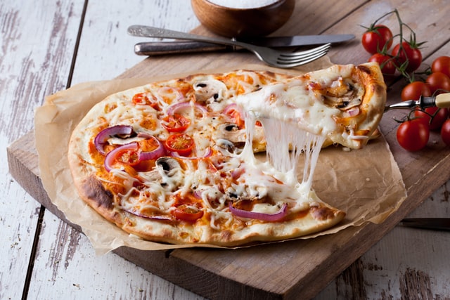 Eine Pizza bei der ein Stück hochgehoben wird