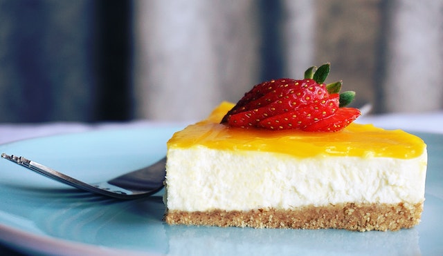 Ein Stück No Bake Kuchen mit Erdbeere und einer Schicht aus passierten Orangen als Verzierung
