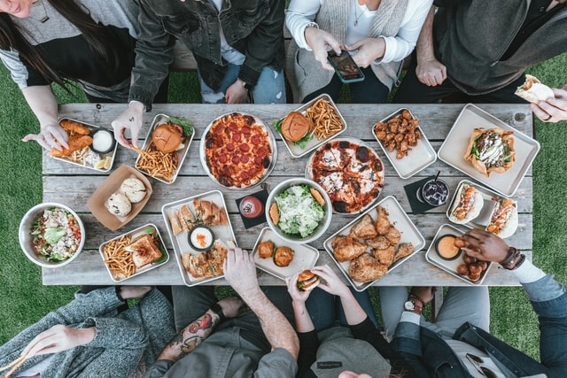 Menschen sitzen an einem Tisch mit viel Essen darauf