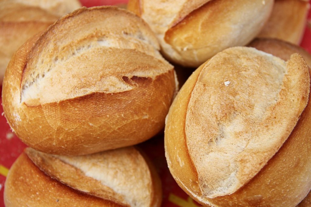 Auf einer roten Tischdecke liegen einige Brötchen, welche oben eingeschnitten sind.