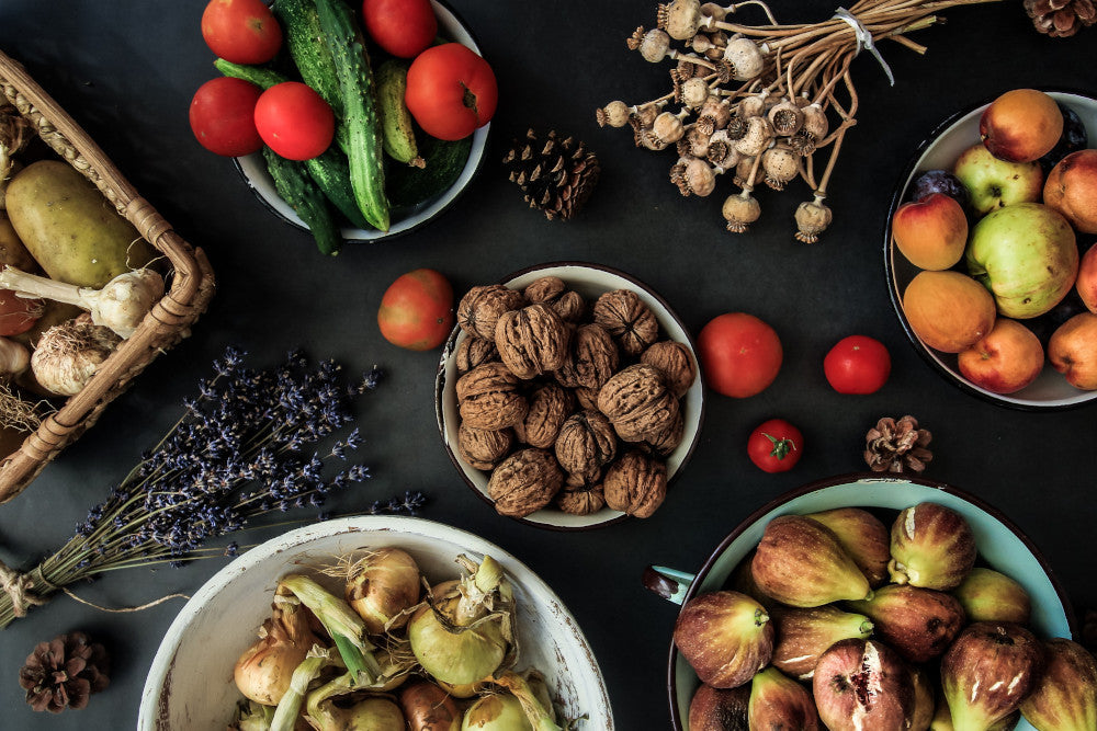 Auf einem schwarzen Untergrund stehen Schüssel befüllt mit Zutaten für Clean Eating, z.B. verschiedene Nüsse, Obst und Gemüsesorten.