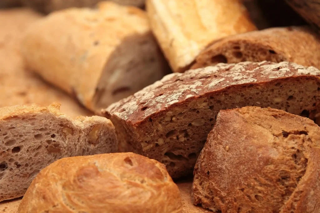 Nahaufnahme verschiedener Brotsorten mit dunkler und heller Kruste auf einem Holztisch