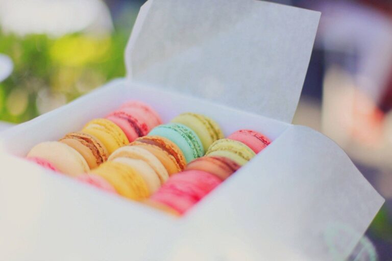 In einem weißen Karton liegen viele bunte Macarons