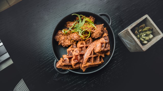 Eine Schüssel mit frittiertem Hühnchen und Waffeln, daneben ein Blumentopf mit einer Sukkulente