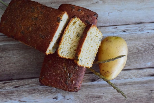 Ein angeschnittenes Brot liegt neben einer Kartoffel