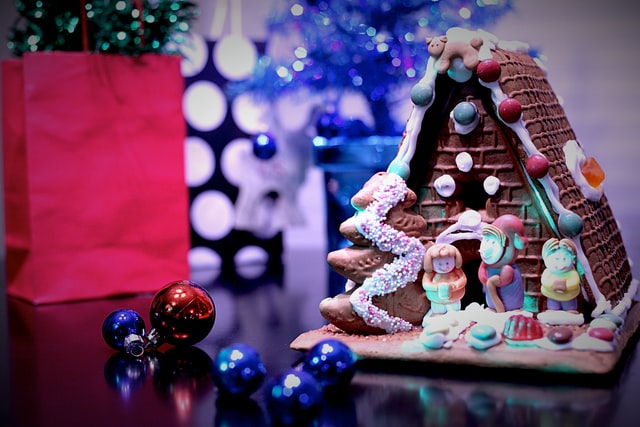 Ein detailliert gestaltetes Lebkuchenhaus steht vor einigen Geschenktüten
