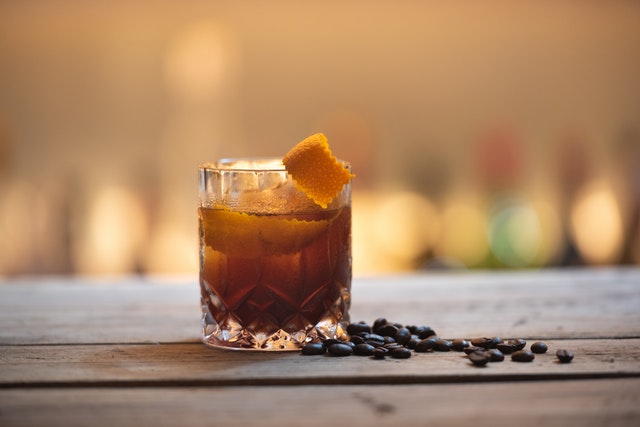 Neben einem Glas Rum liegen einige Kaffeebohnen