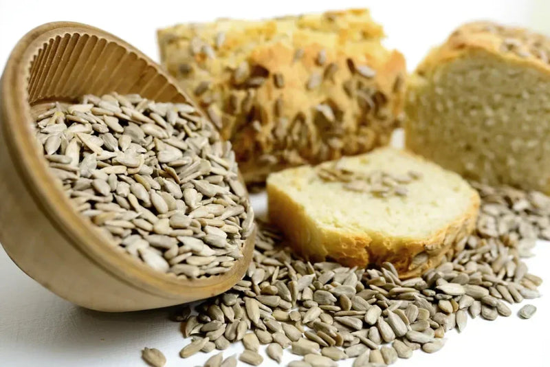 Nahaufnahme von Sonnenblumenkernen und Brot auf einem Tisch.