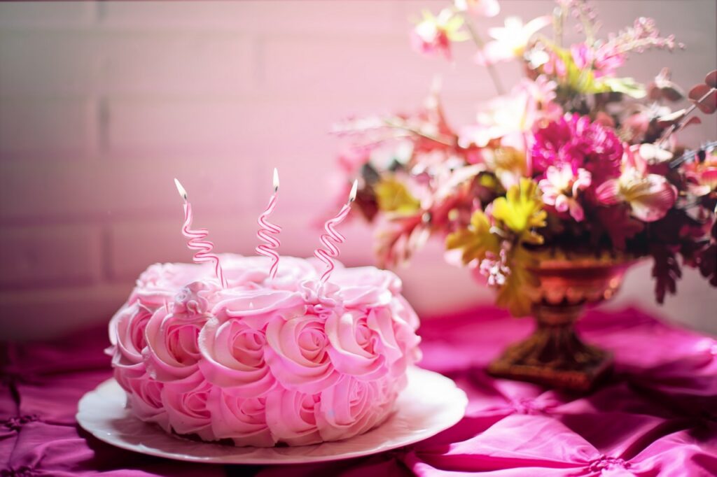 Auf einem Tisch steht eine Torte, welche mit Blumen aus Buttercreme verziert wurde. Daneben stehen echte Blumen.
