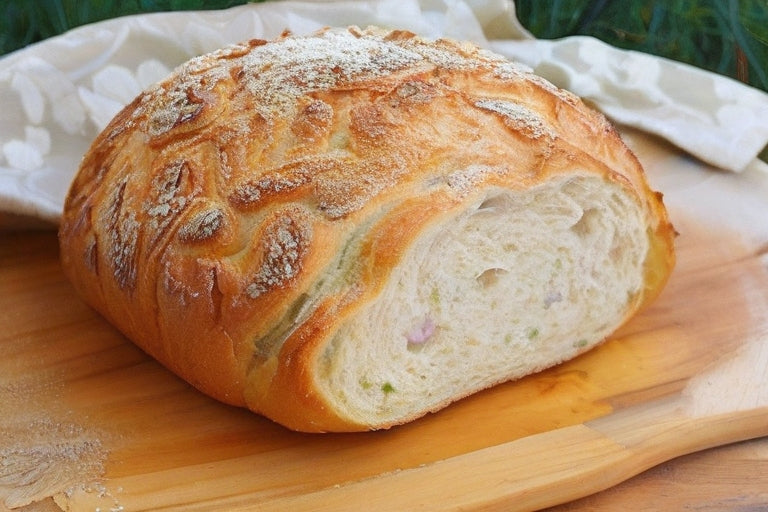 Ein angeschnittenes, helles Zwiebelbrot auf einem Holzbrett