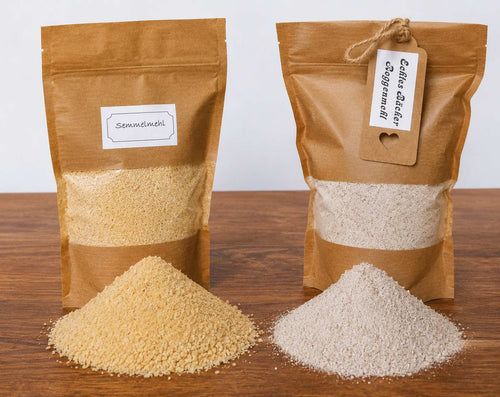 Semmelmehl und Roggenmehl in Tüten verpackt auf einer Holzablage, davor zwei Mehlhaufen