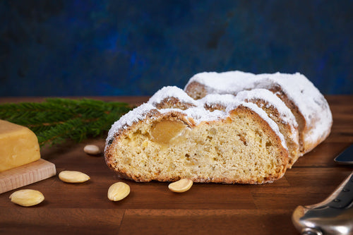Angeschnittener Marzipanstollen auf einem Holzbrett.