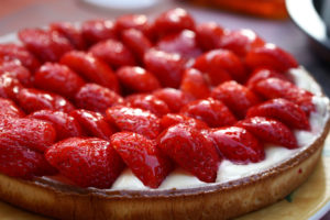 Ein runder Kuchenteig ist mit Pudding und Erdbeeren belegt
