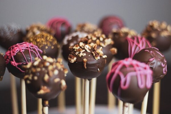 Mit Schokolade überzogene Cake Pops wurden mit pinker Glasur und Nüssen dekoriert