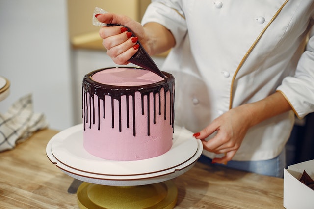 Eine rosane Eistorte wird mit tropfender Schokolade verziert