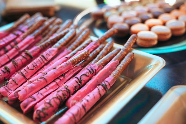 Einige rezel-Stangen dekoriert mit pink eingefärbter Schokolade liegen auf einem Teller