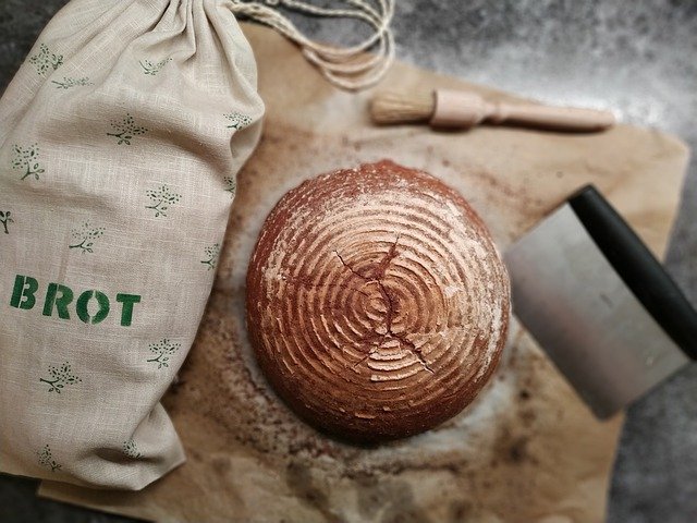Ein Brot liegt neben einem Jutebeutel mit der Aufschrift Brot