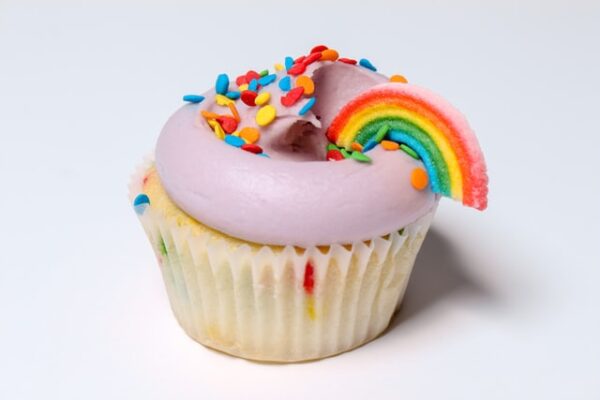 Ein Cupcake wurde mit einem rosa Frosting, einem Regenbogen und einigen Streuseln dekoriert