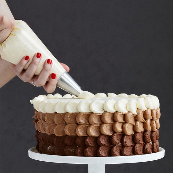 Ein Kuchen wurde mit verschiedenen intensiven Schichten Buttercreme mit Schokolade verziert 
