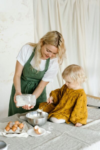 Frau schüttet Mehl in eine Schüssel, kleines Mädchen schaut zu