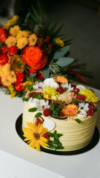 Ein Blumenstrauß im Hintergrund, eine Torte mit Blüten im Vordergrund