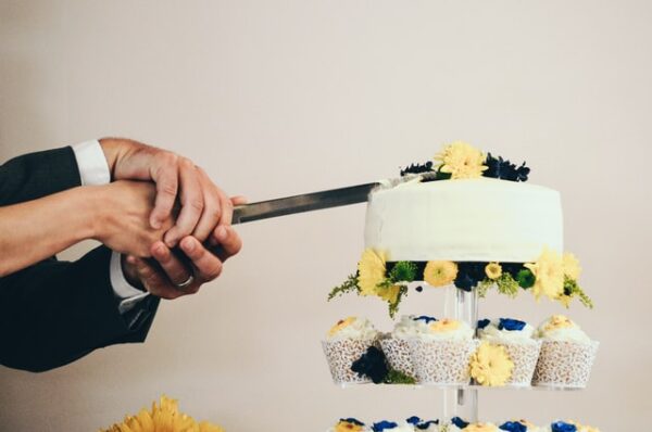 Ein Ehepaar schneidet gemeinsam eine Torte an, die mit Blumen dekoriert ist