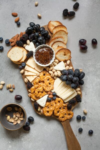 Ein Brett mit Crackern, Käse und Weintrauben