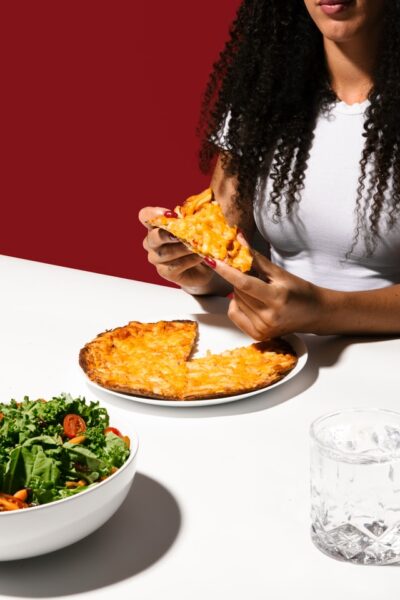 Eine Person isst eine Pizza, vor ihr ein grüner Salat.