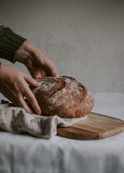 Eine Person legt ein Brot auf ein Brett mit Tuch