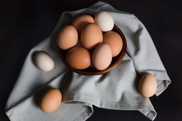 Schüssel mit braunen und weißen Eiern, die auf einem Tuch steht. 