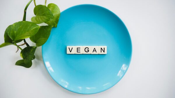 Scrabble-Buchstaben, die das Wort "vegan" formen auf einem blauen Teller