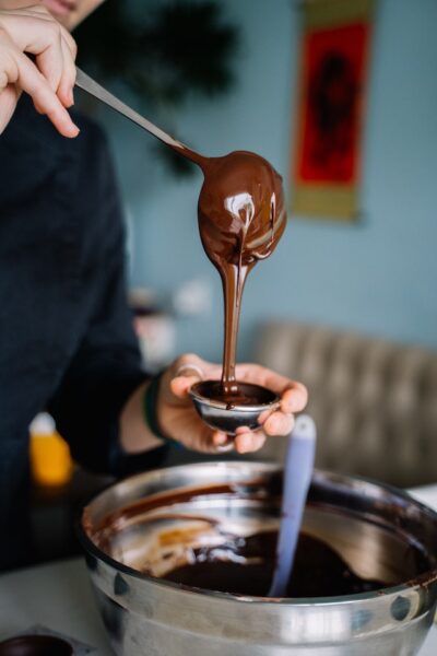 Person füllt flüssige Schokolade in ein Gefäß
