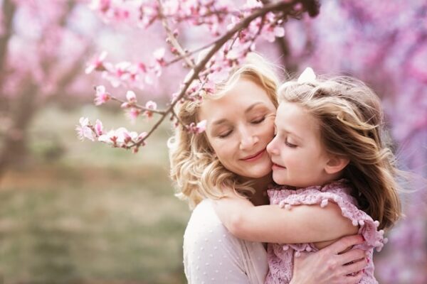 Eine Mutter und Tochter inmitten von rosa Kirschblüten.