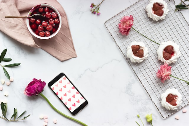 Ein Tisch mit Kirschen, Blumen und einem Handy mit Herzen darauf