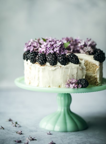 Ein Kuchen mit Frosting, geschmückt mit Brombeeren und Blumen