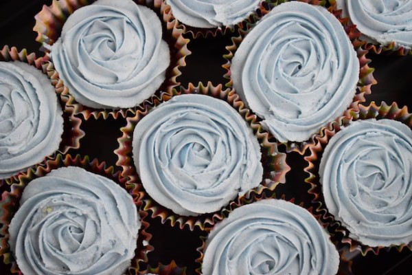 Eine Nahaufnahme von 9 Cupcakes mit blauem Frosting in Rosenblütenform.